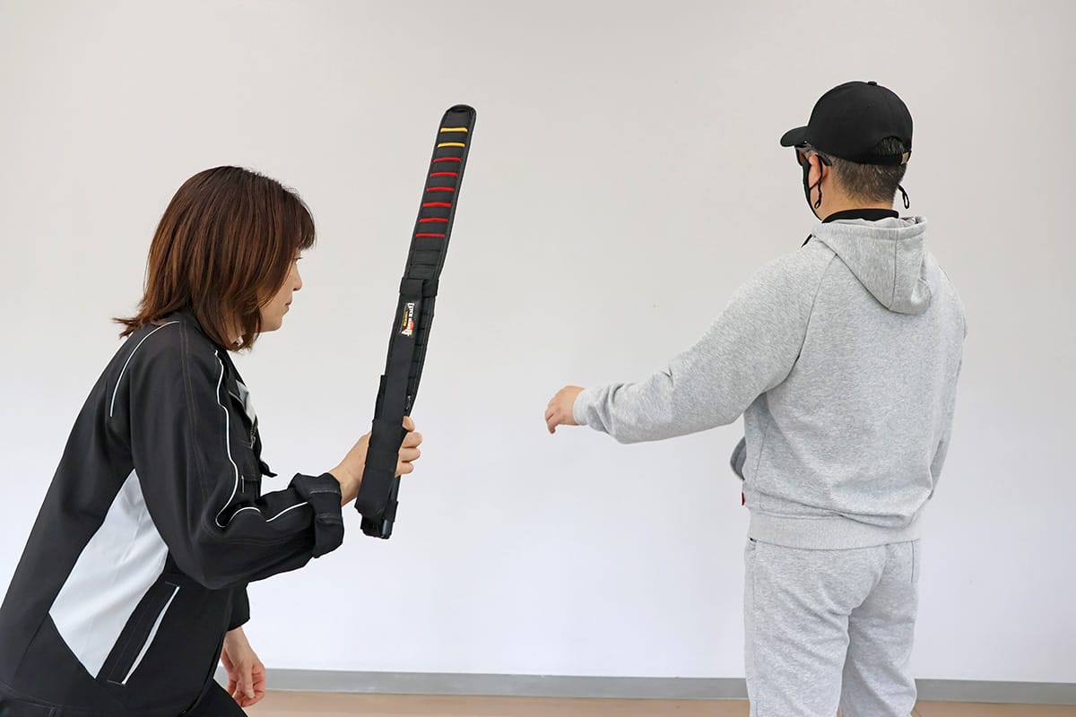 オロチSO7を不審者の腕に叩きつける様子